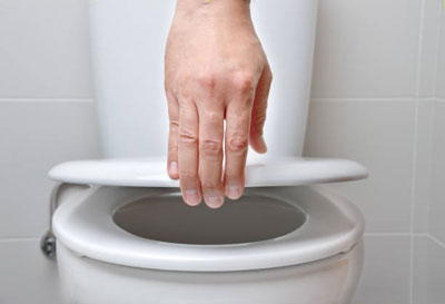 hand closing the lid of a toilet